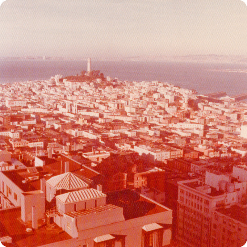 Red-hued, vintage photo of San Francisco with Coit Tower in the background