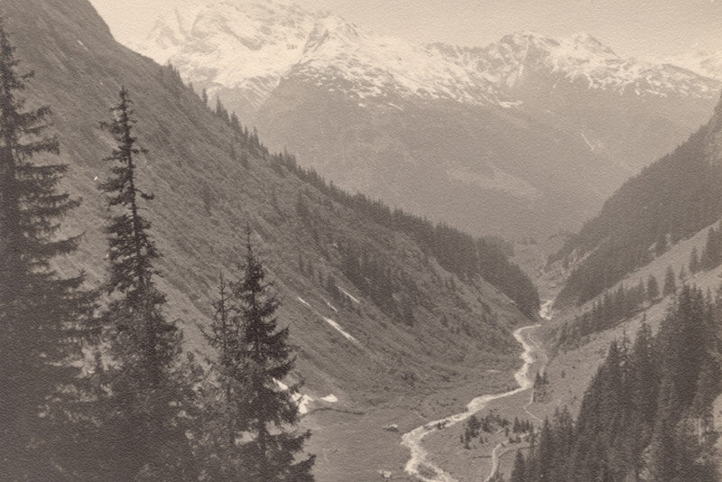 Sepia toned vintage photograph of a beautiful mountainside with trees and a river running through a valley